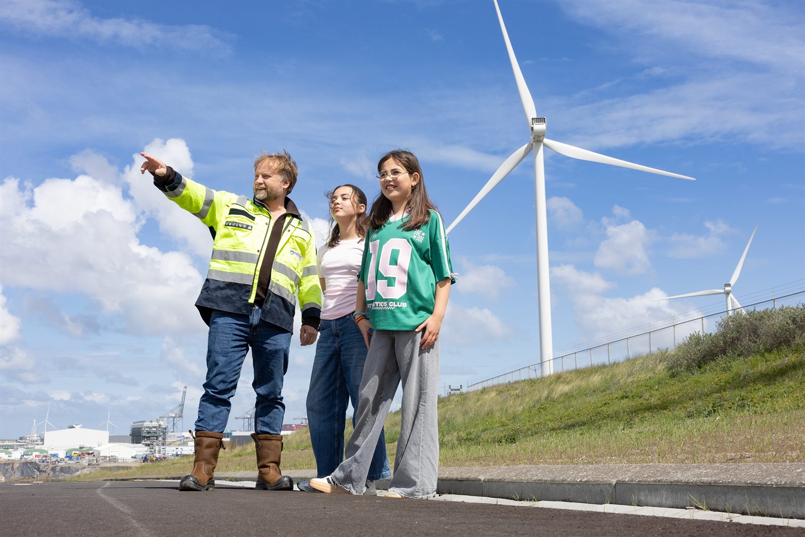 Medewerker geeft uitleg aan kinderen voor een grote windmolen op de Maasvlakte